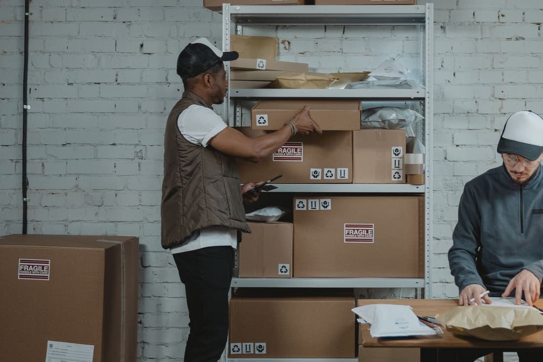 Workers preparing cartons at a packing station, ready for labeled inventory to leave the operation.